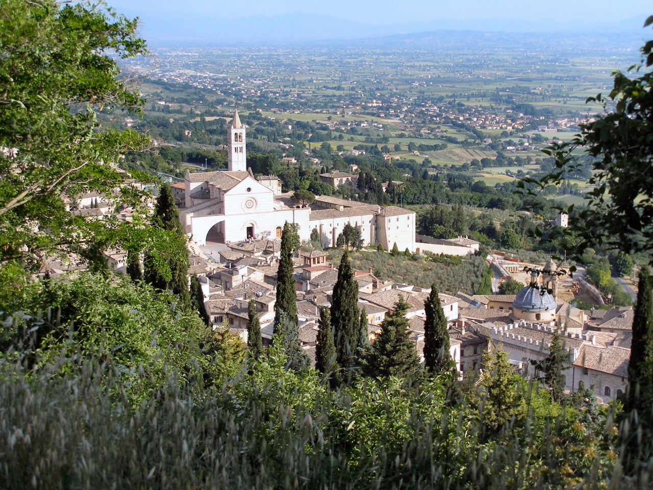 The white Gothic Basilica of Saint Clare above the rooftops of Assisi and the Umbrian plain.