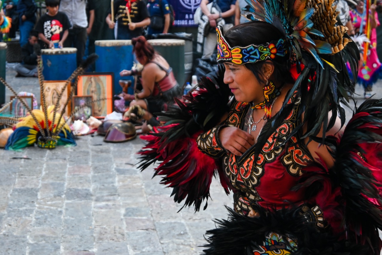 A traditional dancer in feathered regalia before images of Our Lady of Guadalupe on the feast day.