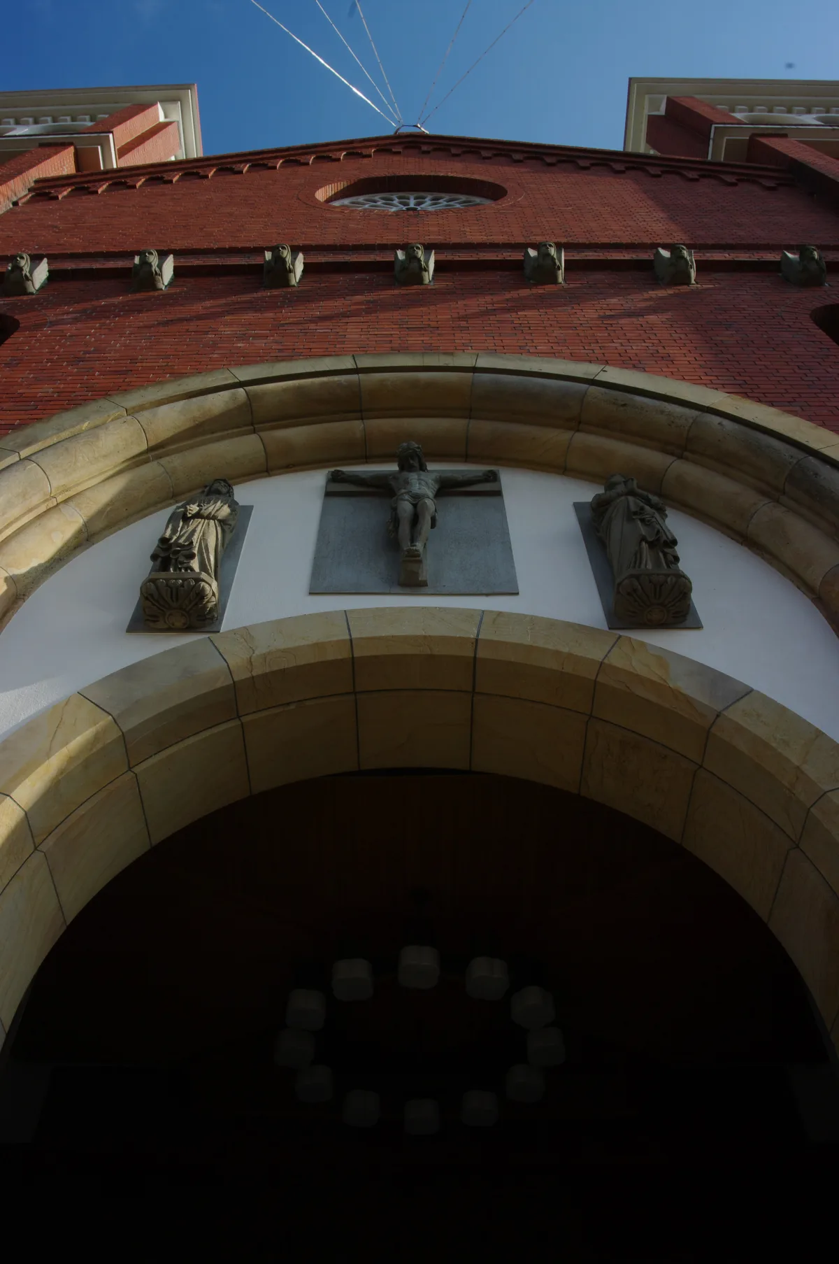The arched west portal of Urakami Cathedral with a crucifixion relief flanked by two weathered stone figures.