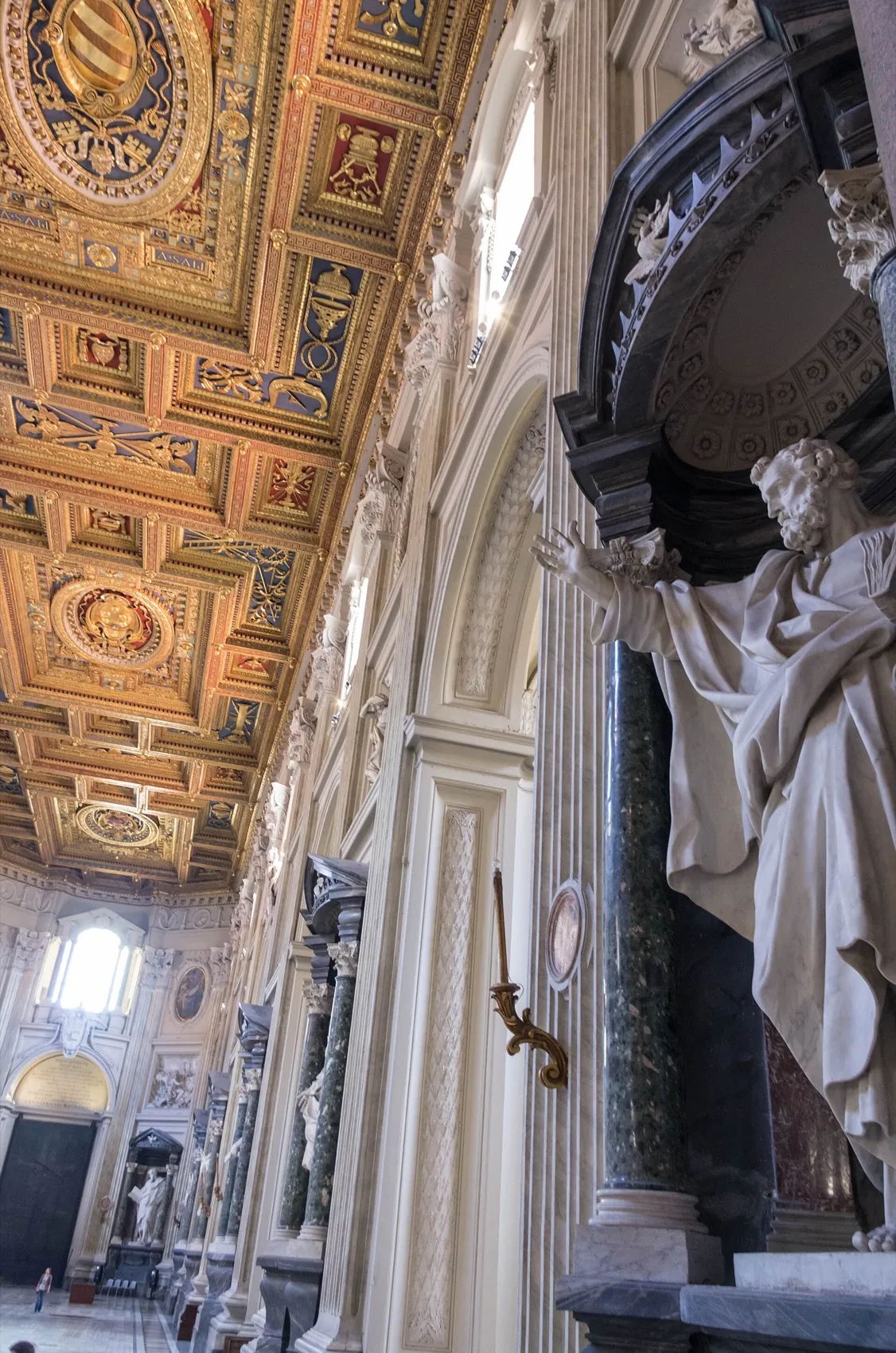 The nave of St. John Lateran with the gilded ceiling and a colossal statue of an Apostle in its niche
