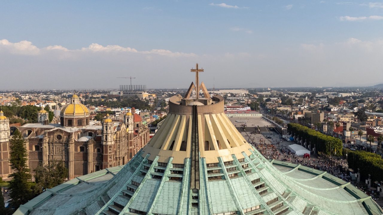 The green roof and crowning cross of the new Basilica of Our Lady of Guadalupe at Tepeyac, with the domes of the old basilica beyond.