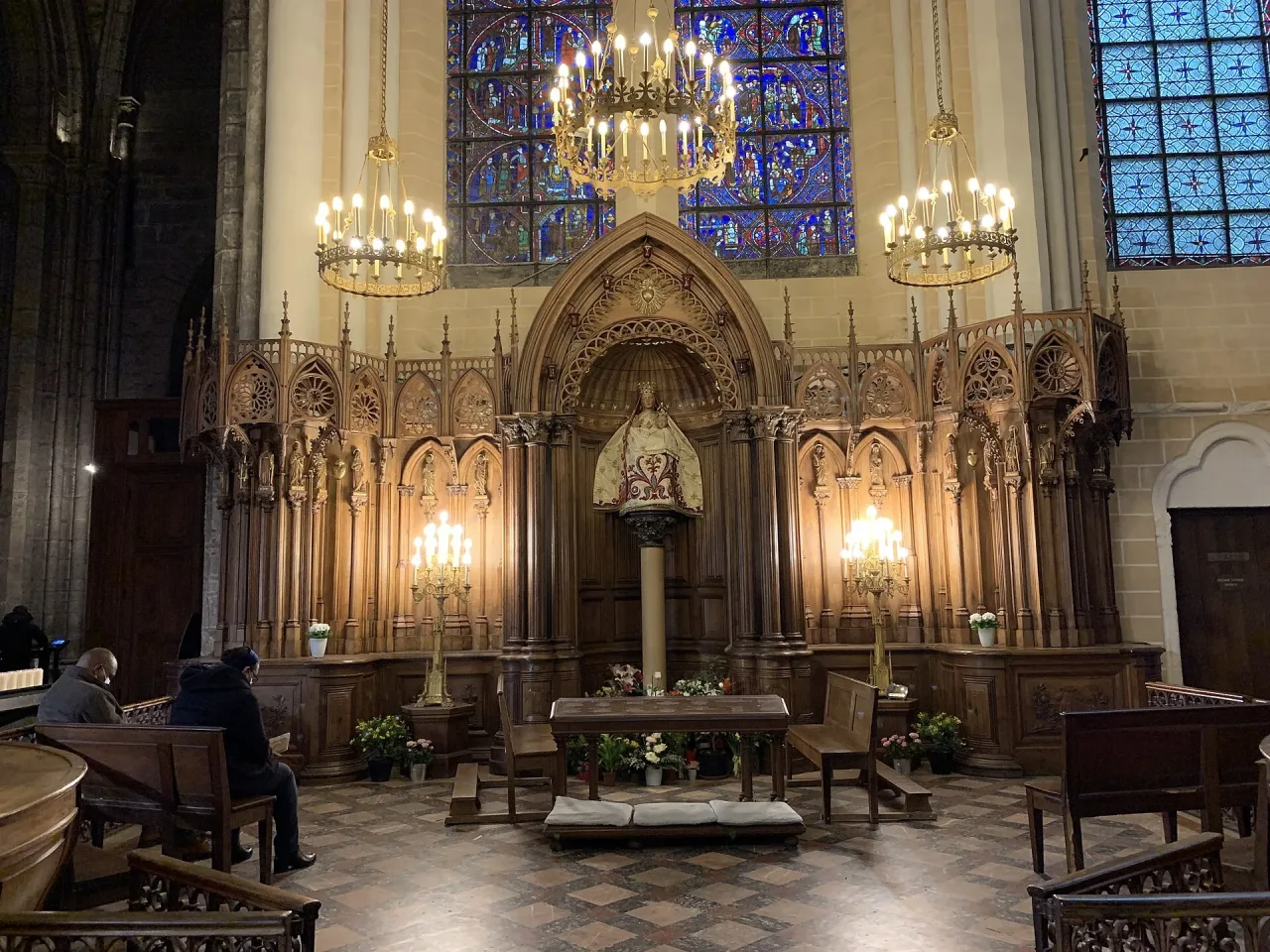 The chapel of Notre-Dame du Pilier in Chartres Cathedral, the clothed statue of the Virgin and Child on its pillar behind a stand of lit candles.