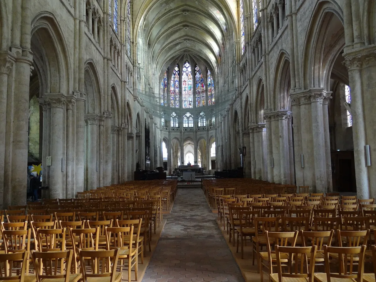 The nave of Église Saint-Pierre in Chartres seen from the west door, its arcades running east toward the lit choir.