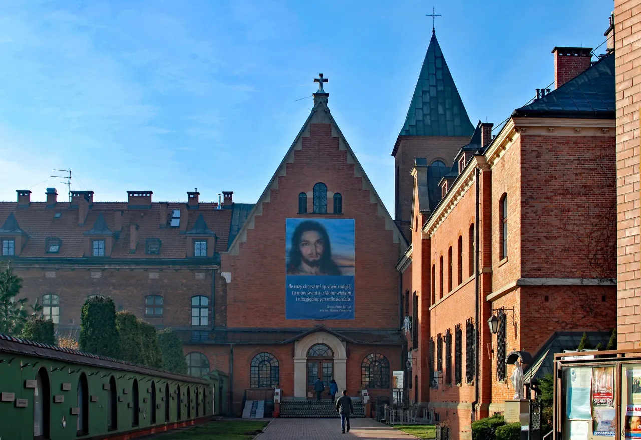 The gable of the convent chapel of St. Joseph at Kraków-Łagiewniki, hung with a large banner of the Merciful Jesus, with pilgrims walking to the door.