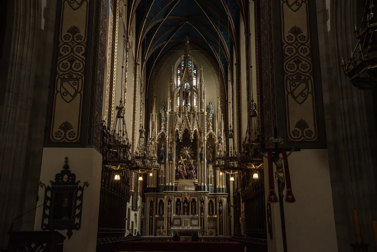 The chancel of the Dominican basilica of the Holy Trinity in Kraków, its neo-Gothic high altar rising under a blue painted vault.