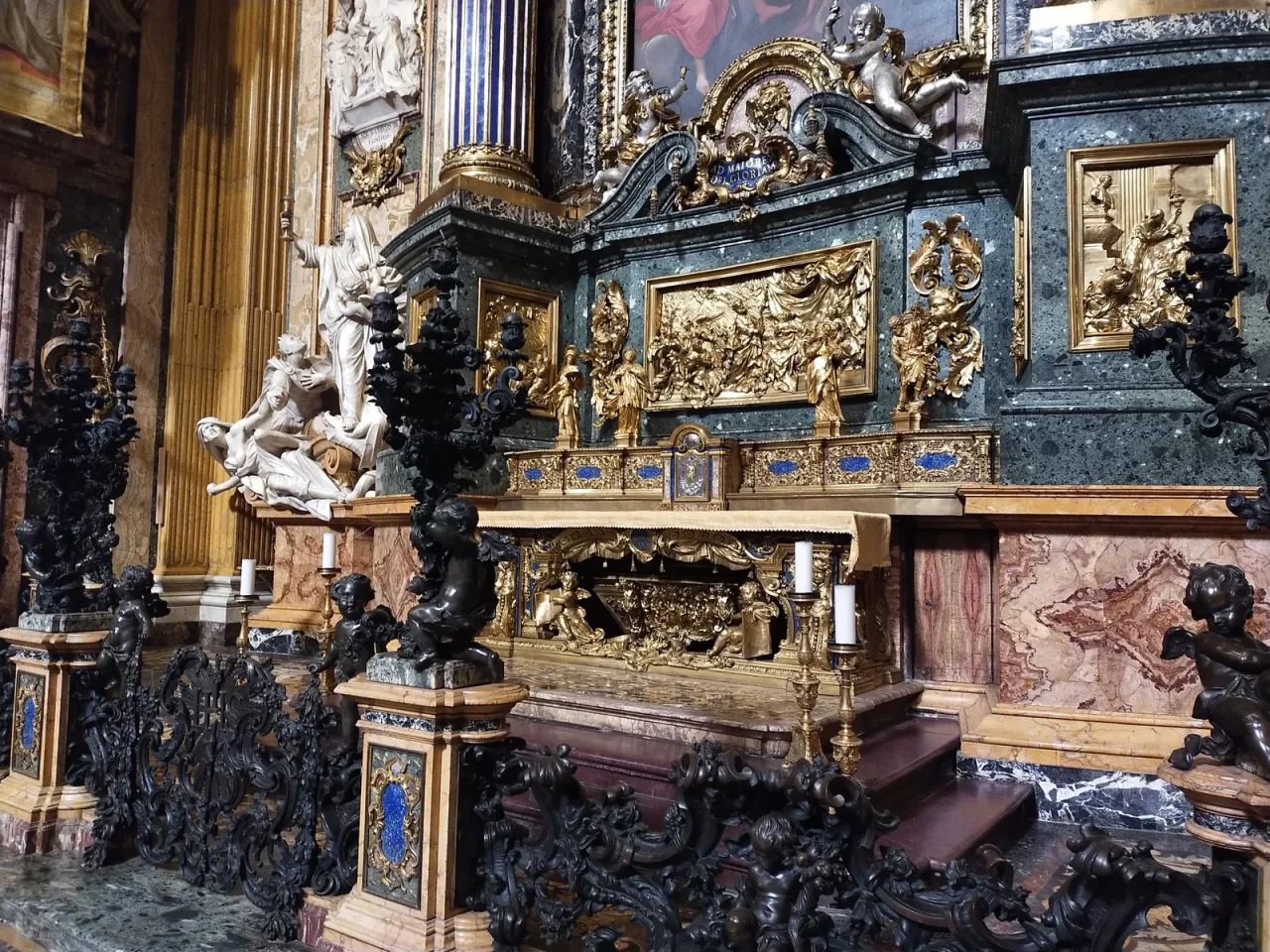 The altar and tomb of Saint Ignatius of Loyola in the Church of the Gesu in Rome, with lapis columns, gilded bronze and the urn beneath the altar table.
