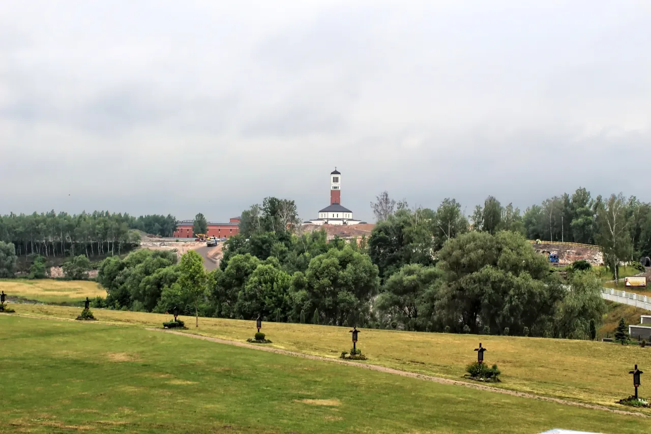 The tower of the Saint John Paul II sanctuary seen across open ground and a line of Stations of the Cross from the tower of the Divine Mercy sanctuary.