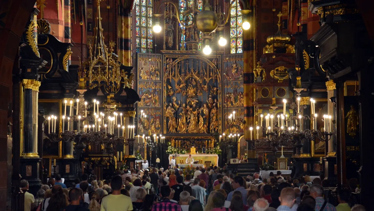 The opened Veit Stoss altarpiece behind the high altar of St. Mary's Basilica during Mass on the feast of the Assumption, with a full congregation.