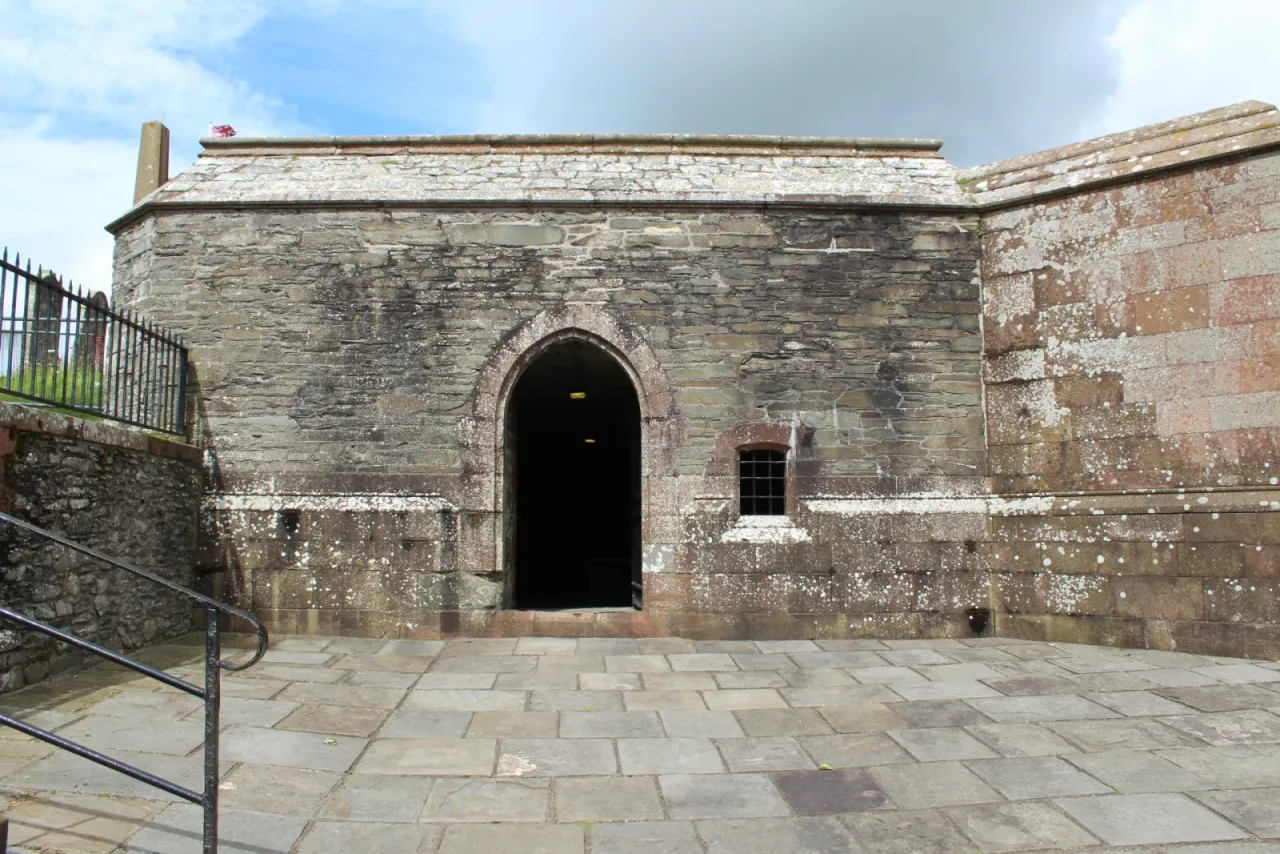 The low stone exterior of the vaulted crypt at Whithorn Priory, with its pointed doorway open to visitors.