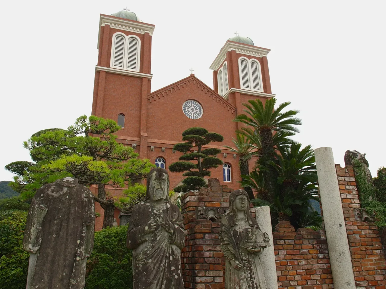 Stone saints damaged in the 1945 bombing stand on a fragment of brick wall in front of the rebuilt Urakami Cathedral.