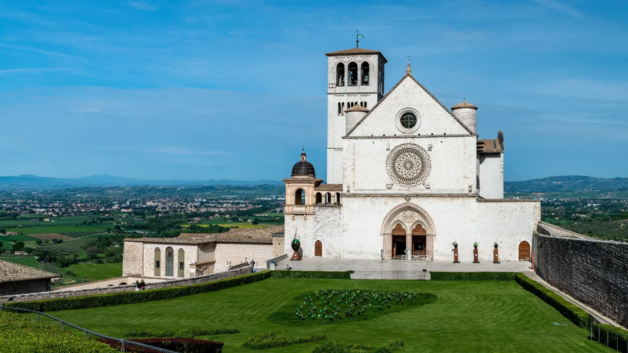 The Basilica of Saint Francis and the Sacred Convent extending along the western edge of Assisi above the Umbrian landscape.