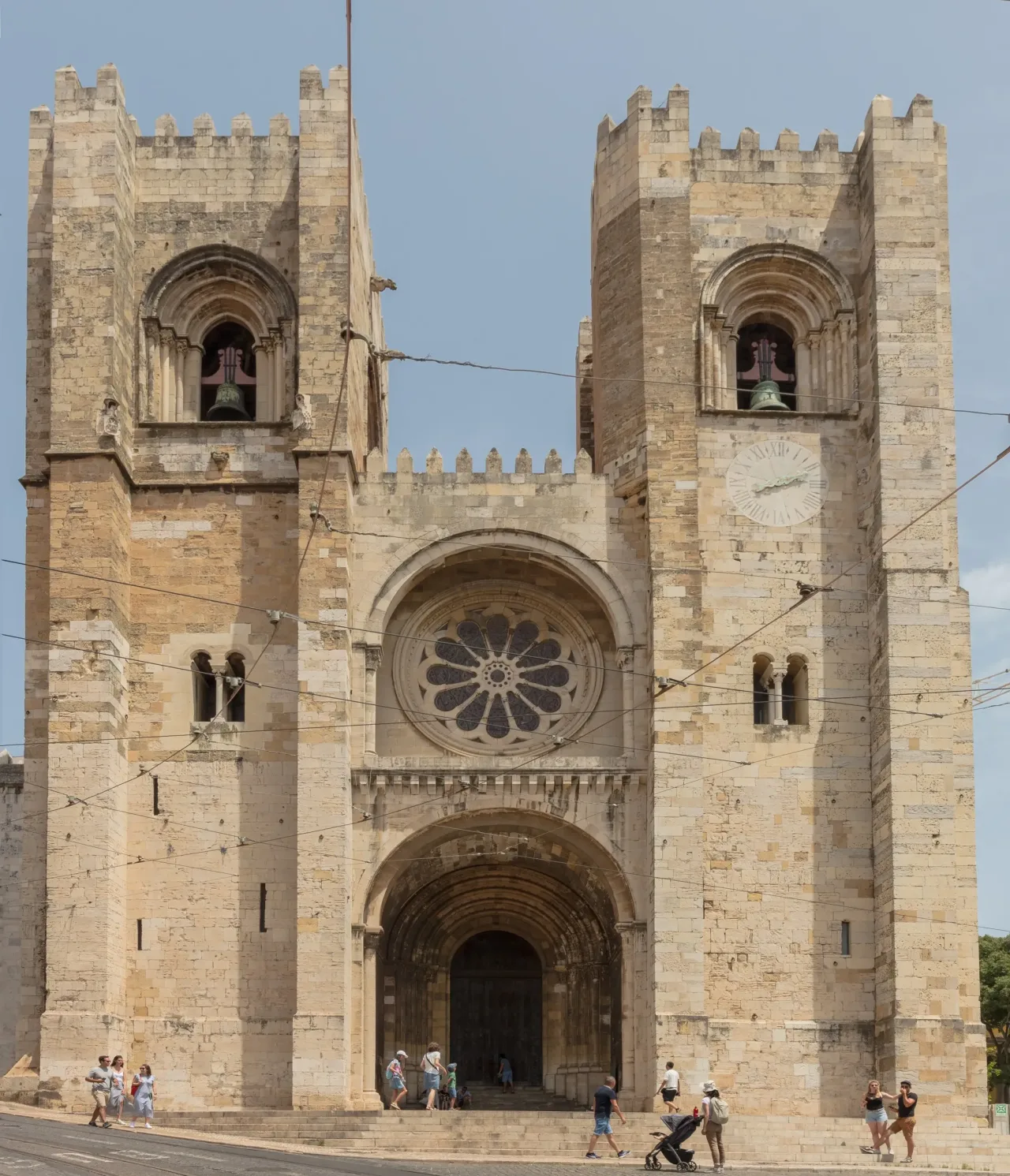 The fortress-like west front of Lisbon Cathedral, its two Romanesque bell towers flanking a rose window above the main portal.