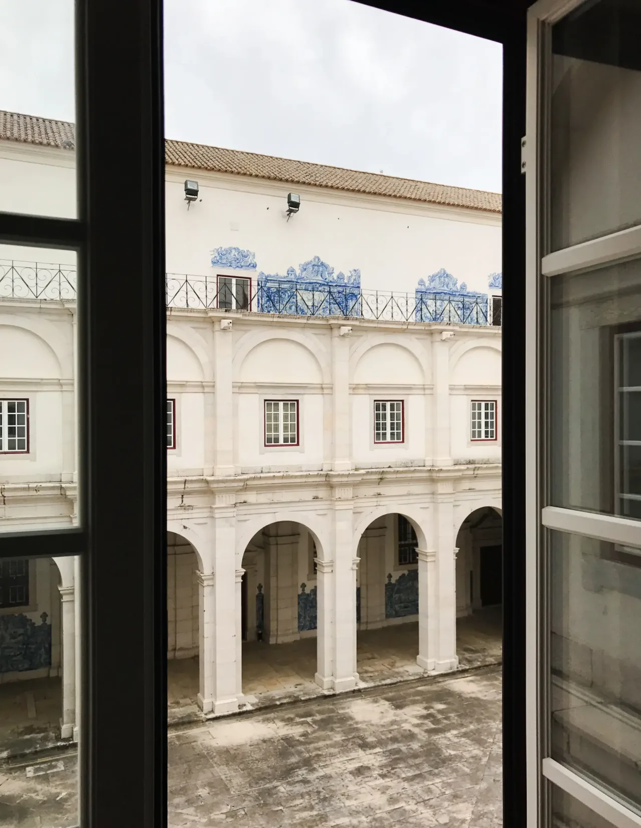 The two-storey arcaded cloister of São Vicente de Fora, its lower walls lined with blue and white azulejo panels.
