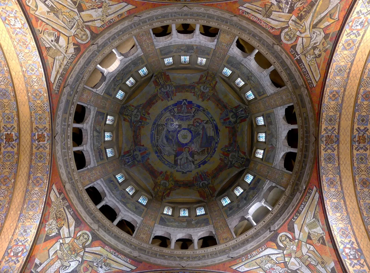 The inside of the dome of the Basilica of Sainte-Thérèse in Lisieux, its mosaic drum and windows seen from the floor below.