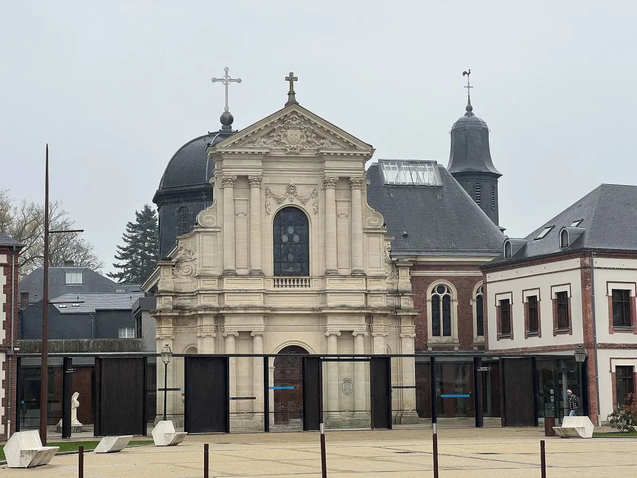 The classical stone front of the chapel of the Carmel of Lisieux seen across its forecourt, with the monastery roofs and bell turret behind.