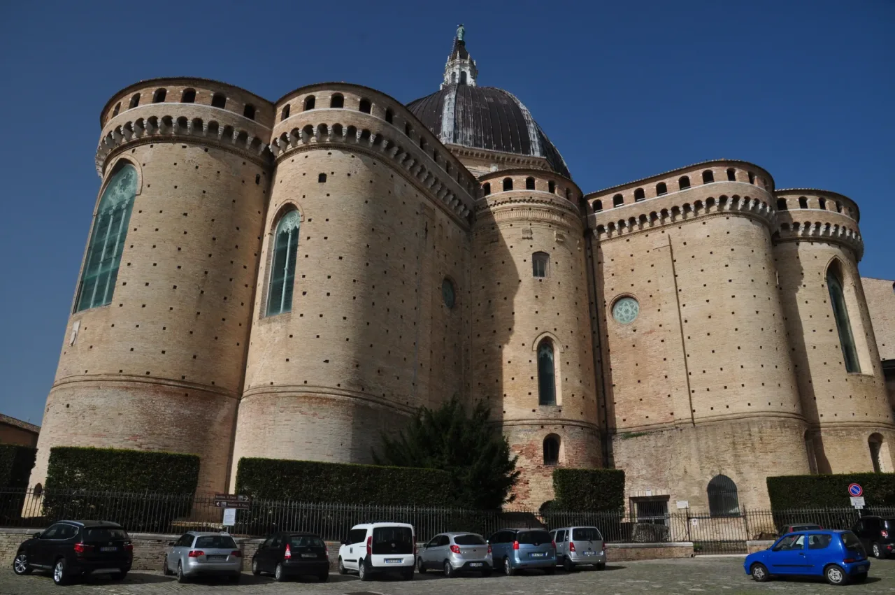 The brick east end of the basilica at Loreto, with round apses topped by battlements and a covered wall-walk, and the lead dome rising behind.
