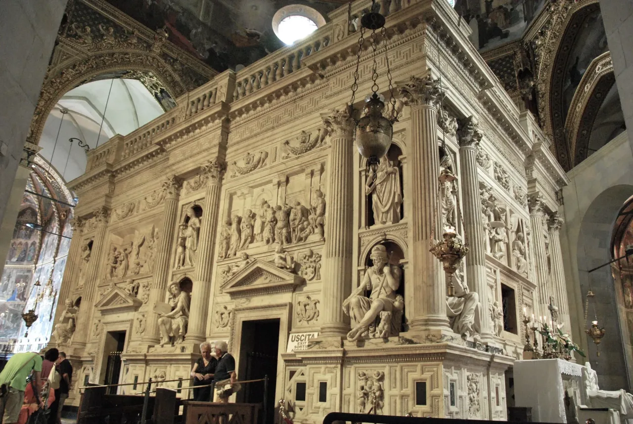 The tall carved white marble enclosure standing beneath the basilica dome, with reliefs, columns, statues in niches, and a low doorway at its base.
