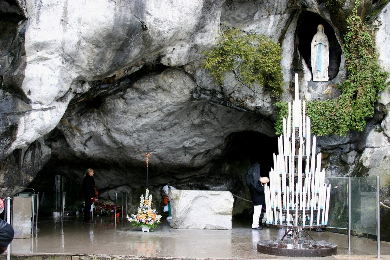 Pilgrims praying before the Grotto of Massabielle at Lourdes.
