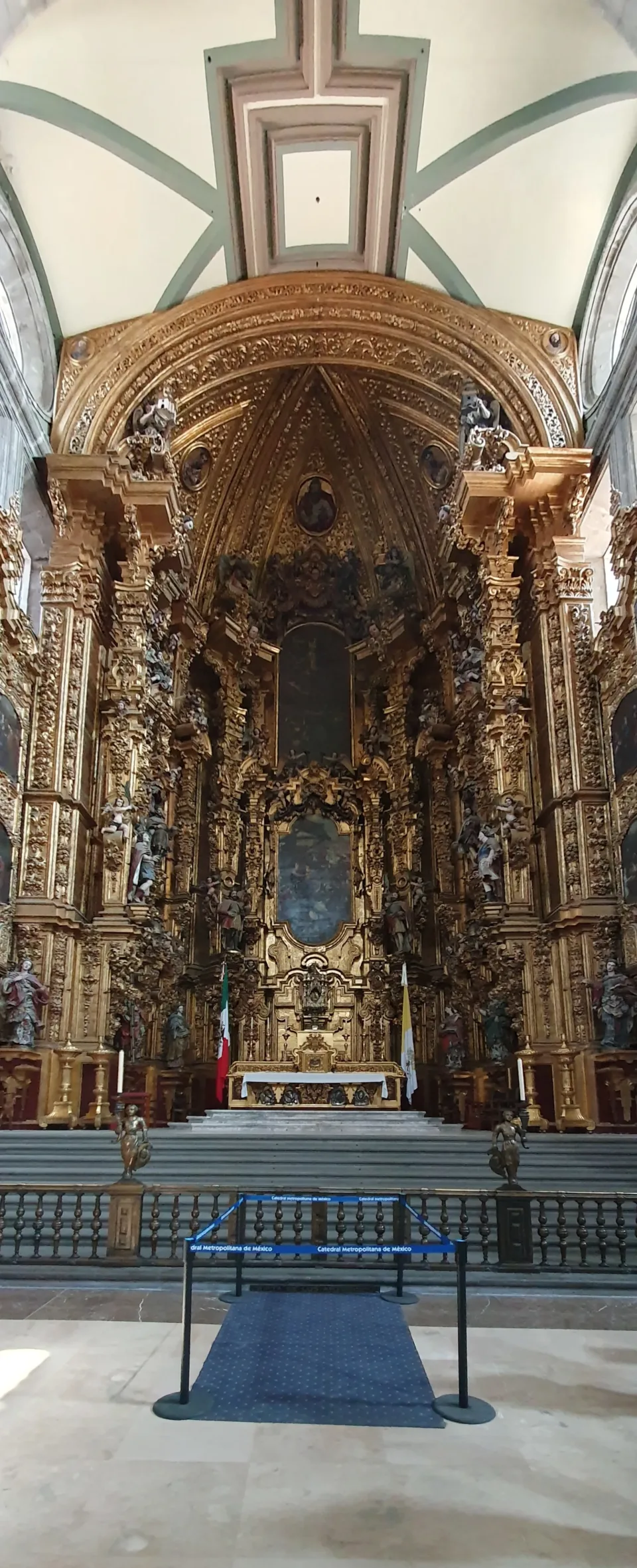 The gilded Altar of the Kings in the apse of Mexico City Cathedral, a tall carved and gold-leafed retablo rising into the vault behind the high altar.