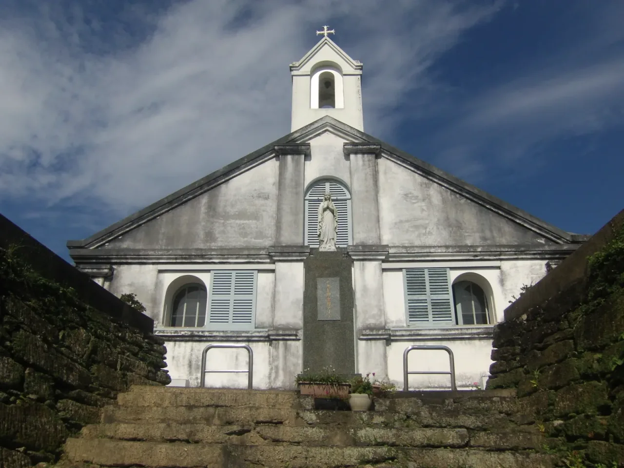 The rear of Shitsu Church against the steep wooded slope that rises directly behind it.