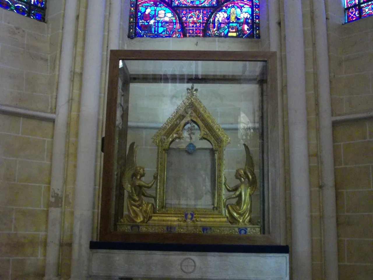 The gilded reliquary of the Veil of the Virgin in Chartres Cathedral, flanked by kneeling angels beneath the stained glass.