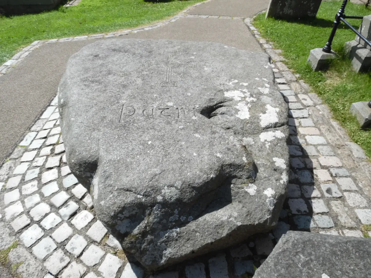 The granite slab marking Saint Patrick's grave in the churchyard at Downpatrick, carved with a ringed cross and the name Patric.
