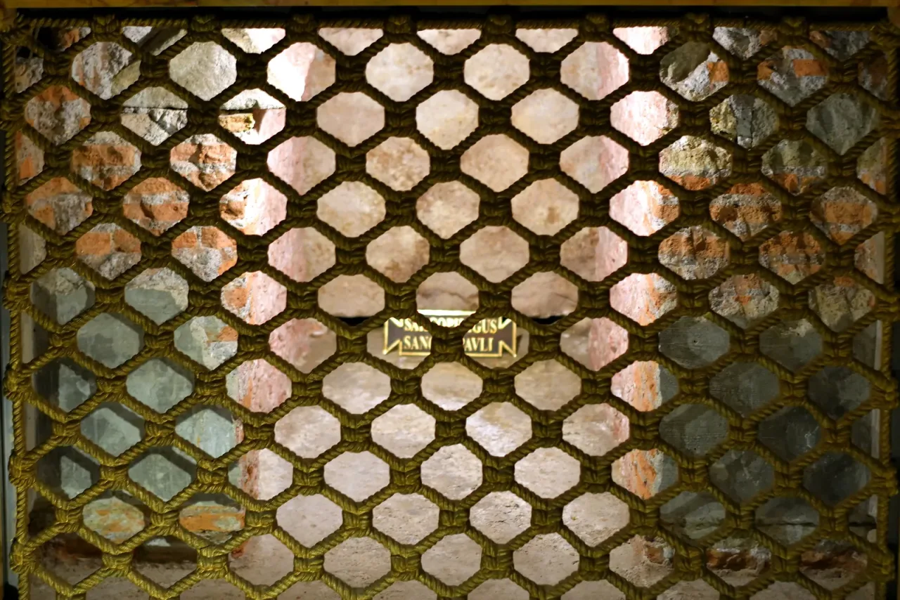 The sarcophagus beneath the papal altar of the Basilica of Saint Paul Outside the Walls in Rome, seen through the bronze lattice, with the plaque naming Paul the Apostle.