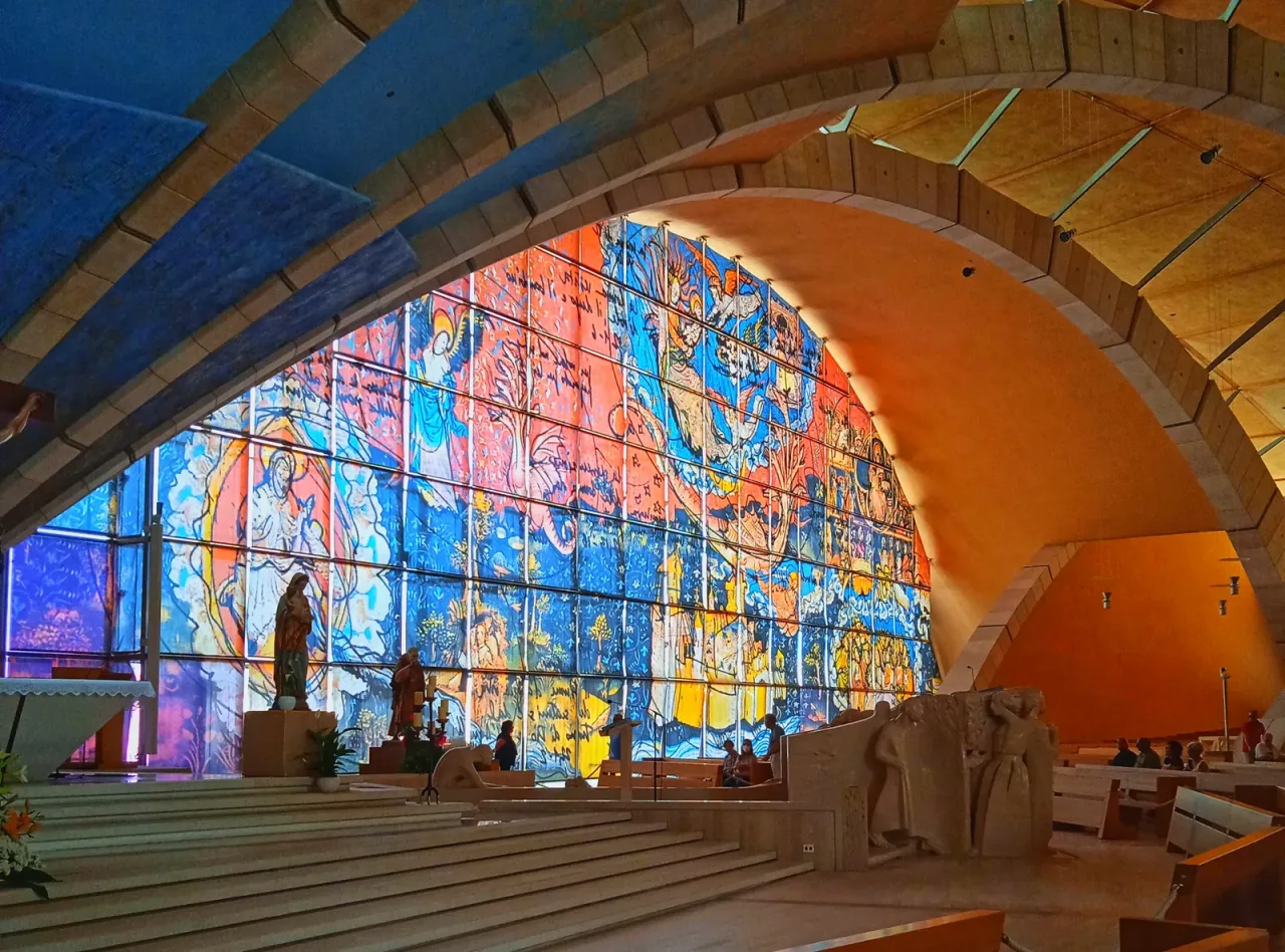 The interior of the church of San Pio da Pietrelcina at San Giovanni Rotondo, with its curved roof and the great stained glass wall above the sanctuary.