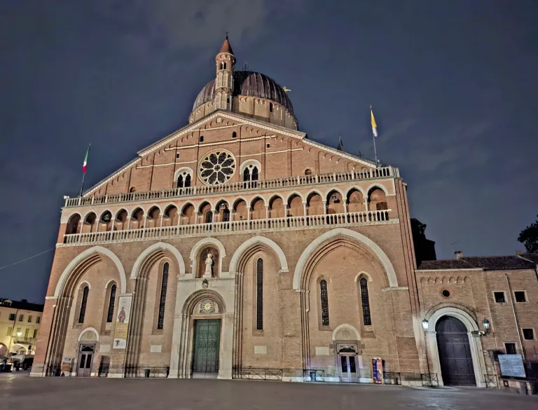 The domes and brick facade of the Basilica of Saint Anthony in Padua at dusk.