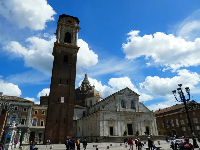The marble facade and bell tower of Turin Cathedral across its piazza.