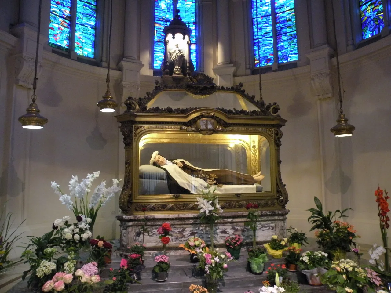 The reliquary shrine of Saint Thérèse in the chapel of the Carmel of Lisieux, a recumbent figure beneath a gilded canopy.