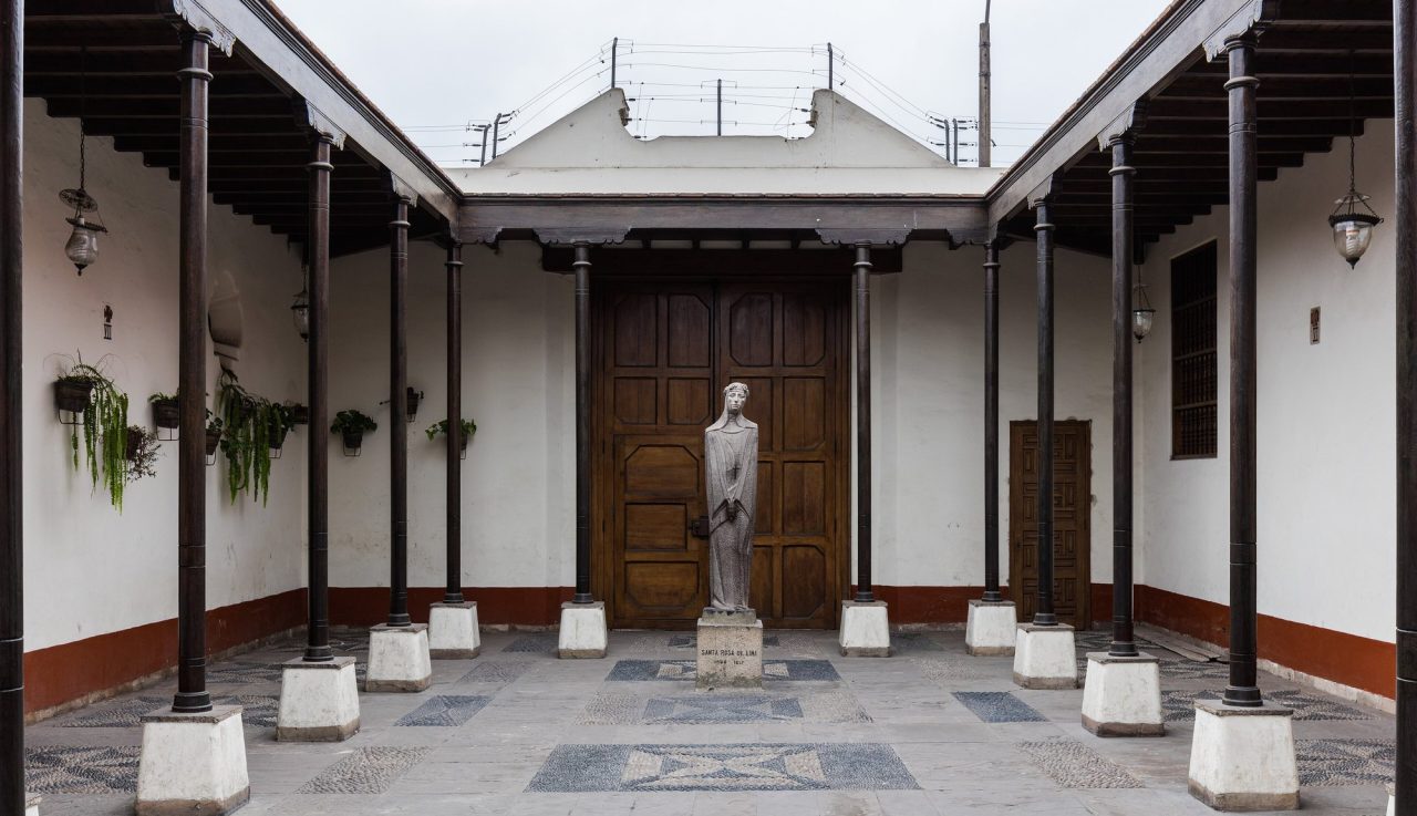 The colonnaded courtyard of the Sanctuary of Saint Rose of Lima, with the statue of the saint before the carved doors.