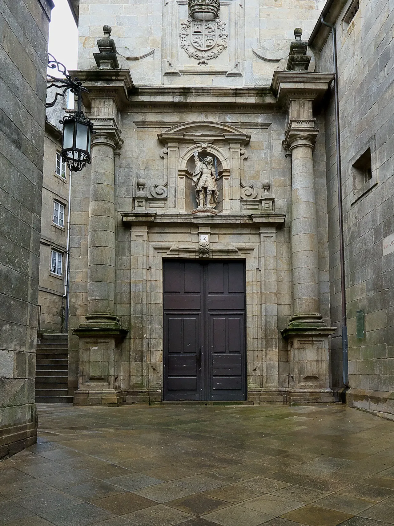 The Baroque doorway of the church of San Paio de Antealtares on the Rúa Sacra, a statue of Saint Pelagius set in a niche above the closed timber doors.